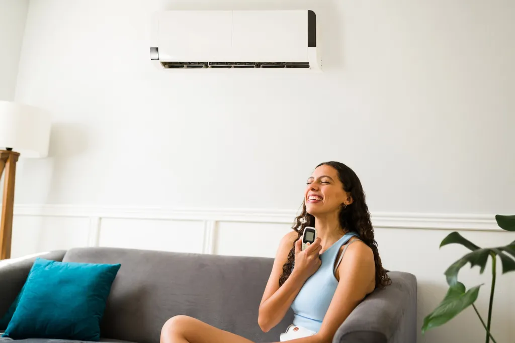Happy woman sitting on couch with air condition above her